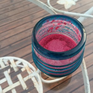 glass tumbler containing a beet cocktail, top view on glass tabletop
